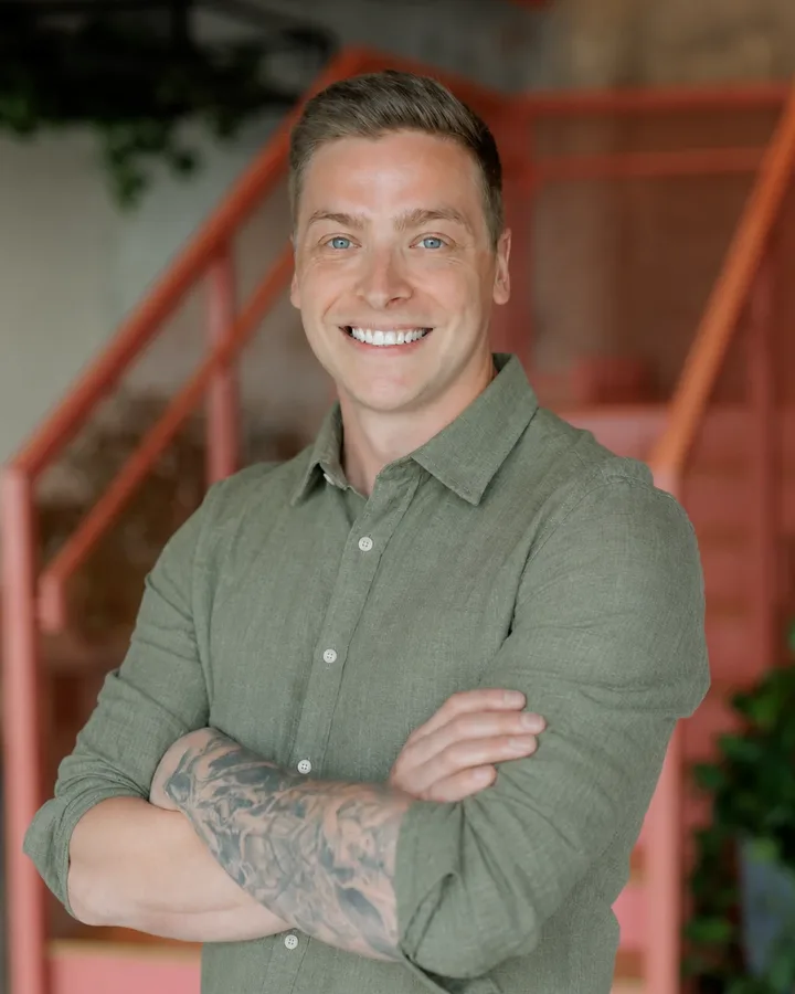 Ash Whitehair, smiling, with his arms folded